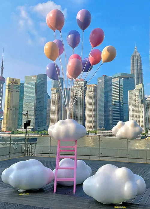 outdoor sculpture of balloons and clouds placed in the city park